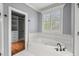Bright bathroom with a large tub, shuttered window, and walk in closet at 5900 Orchid Valley Rd, Raleigh, NC 27613