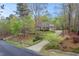 Brick home surrounded by mature trees, featuring a long driveway and lush landscaping at 5900 Orchid Valley Rd, Raleigh, NC 27613