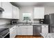 A kitchen with white cabinets and stainless steel appliances, complemented by granite countertops and hardwood flooring at 6102 Coronado Ln, Durham, NC 27713
