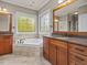 Bathroom featuring a soaking tub, decorative windows, granite countertops, and wood cabinetry at 642 Bear Tree Creek, Chapel Hill, NC 27517