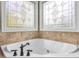Close-up of a white bathtub featuring decorative windows and bronze fixtures at 642 Bear Tree Creek, Chapel Hill, NC 27517