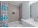 Bathroom featuring tub and shower combo with gray tile and blue accents at 7715 Bernadette Ln, Raleigh, NC 27615