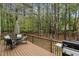 Well-kept wooden deck features a barbeque and patio seating, with a forested yard in the background at 8 Queensland Ct, Durham, NC 27712