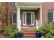 Close-up of a brick front porch with white railings, plants, and a glass front door at 8 Queensland Ct, Durham, NC 27712