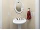 Classic powder room featuring a pedestal sink, oval mirror, and neutral tones at 9026 Privette Hill Ln, Spring Hope, NC 27882