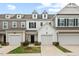View of townhome exteriors showing the garages and small landscaped front lawns under a cloudy blue sky at 95 Little Leaf Lane Ln, Clayton, NC 27527