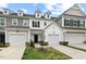 Townhome exteriors featuring garages and small landscaped lawns under a cloudy blue sky at 95 Little Leaf Lane Ln, Clayton, NC 27527