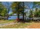 Lakeside backyard featuring a stone pathway, mature trees, and waterfront access at 955 Sagamore Dr, Louisburg, NC 27549