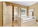 Bathroom with a glass shower, soaking tub, and stained-glass window providing natural lighting at 955 Sagamore Dr, Louisburg, NC 27549