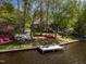 Scenic waterfront property featuring a private dock with outdoor seating, surrounded by colorful landscaping and mature trees at 955 Sagamore Dr, Louisburg, NC 27549