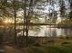 Scenic lake view at sunset, framed by trees and lush greenery, offering a tranquil ambiance at 955 Sagamore Dr, Louisburg, NC 27549
