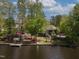 Waterfront property featuring a lush, landscaped yard sloping to a private dock on a calm lake, surrounded by mature trees at 955 Sagamore Dr, Louisburg, NC 27549