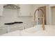 Bright kitchen featuring white cabinets, countertops, and a stylish faucet with a modern vent hood at 0006 Tallulah Loop Lane, Cedar Grove, NC 27231