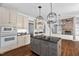 An open kitchen with updated appliances, a large island, and a view of the living room with a stone fireplace at 101 Preston Arbor Ln, Cary, NC 27513