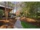 Beautiful backyard featuring a stone pathway, mature trees, covered patio, and outdoor grill at 102 Kamprath Pl, Cary, NC 27519