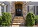 Close-up of the front door under a stone archway with stone steps and manicured bushes at 102 Kamprath Pl, Cary, NC 27519