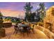 Inviting backyard with a stone fireplace, dining area, and hot tub with charming string lights at 104 Vervain Way, Holly Springs, NC 27540