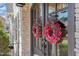 Close-up of double front doors adorned with floral wreaths, enhanced by stone facade at 104 Vervain Way, Holly Springs, NC 27540