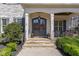 Inviting front porch with stone steps, decorative wreaths, and well-manicured landscaping at 104 Vervain Way, Holly Springs, NC 27540