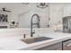 Kitchen island features a stainless steel sink and faucet with a view of the adjacent living room at 104 Vervain Way, Holly Springs, NC 27540
