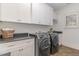 Laundry room with modern, stainless steel washer and dryer, and custom white cabinets at 104 Vervain Way, Holly Springs, NC 27540