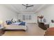 Spacious main bedroom with tray ceilings, a ceiling fan, and a sitting area near the window at 104 Vervain Way, Holly Springs, NC 27540