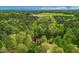 Aerial view of a home surrounded by lush trees, located near fields and paved roads at 105 Hobson Pl, Louisburg, NC 27549