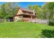Spacious backyard featuring a deck, a swimming pool, and a lush green lawn, surrounded by trees at 105 Hobson Pl, Louisburg, NC 27549