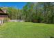 Expansive backyard with lush green grass, a deck with a pool, and a storage shed surrounded by trees at 105 Hobson Pl, Louisburg, NC 27549