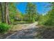 Long gravel driveway leading to a secluded home surrounded by mature trees and natural landscape at 105 Hobson Pl, Louisburg, NC 27549