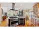 Spacious kitchen showcasing a central island with modern cooktop, wine fridge, stone fireplace and hardwood floors at 11 Swallow Tail Ct, Pittsboro, NC 27312