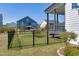 Landscaped backyard featuring a black metal fence, grass, and a cozy covered porch at 1165 Saint Cloud Loop, Apex, NC 27523