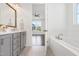 Bright bathroom boasts a soaking tub and double sink vanity with gray cabinets, perfect for relaxation at 1165 Saint Cloud Loop, Apex, NC 27523