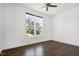 Bright bedroom featuring hardwood floors, a ceiling fan, and a large window with neighborhood views at 1165 Saint Cloud Loop, Apex, NC 27523