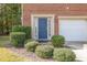 Charming brick home featuring a blue front door, manicured bushes, and a bright garage at 117 Gallent Hedge Trl, Apex, NC 27539