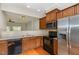 Traditional kitchen with wood cabinetry, stainless steel refrigerator, and view into the living room at 117 Gallent Hedge Trl, Apex, NC 27539