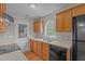 Kitchen with wood cabinets, stainless steel sink, black appliances, and door to the backyard at 120 Stillmeadow Dr, Louisburg, NC 27549