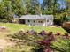 This backyard is spacious with a tree line, green grass, colorful plants, and play equipment at 1307 Crabapple Ln, Raleigh, NC 27607