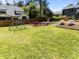 Large backyard with lush grass, a wooden fence, blooming plants, and play equipment at 1307 Crabapple Ln, Raleigh, NC 27607