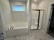 Bright bathroom featuring a soaking tub, walk-in shower, and a modern window at 14 Cricket Hill Way, Benson, NC 27504