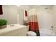 Well-lit bathroom featuring a shower-tub with colorful curtain, a white sink and toilet at 1415 Quarter Pt, Raleigh, NC 27615