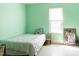 Sunny bedroom with light green walls, white floors, and a twin bed by a window at 1556 Pleasants Rd, Wendell, NC 27591