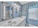 Well-lit bathroom with double vanity, framed mirrors, and a shower with a glass door, all in a blue color scheme at 1600 S Wade Ave, Garner, NC 27529