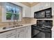 Practical kitchen with white cabinets, black appliances, and a view to the outdoors at 1600 S Wade Ave, Garner, NC 27529