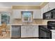 Kitchen with white cabinets, stainless steel dishwasher, black appliances, and a cozy eating nook at 1600 S Wade Ave, Garner, NC 27529