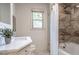 Bright bathroom featuring a modern vanity and a bathtub with a tiled surround and shower at 1705 Lord Ashley Dr, Sanford, NC 27330