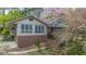 Charming home featuring a brick foundation and a bright sunroom surrounded by lush landscaping and flowering trees at 1705 Lord Ashley Dr, Sanford, NC 27330