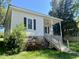 Charming home featuring a covered porch, black shutters, landscaped yard, and a staircase leading to the entrance at 1716 Turner St, Roxboro, NC 27573