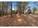 View of the backyard showing a house with a deck surrounded by trees and fallen leaves at 19 Lansgate Ct, Durham, NC 27713