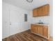 Compact kitchenette featuring a door, wood-look floors, and upper and lower cabinets at 203 W Pilot St, Durham, NC 27707
